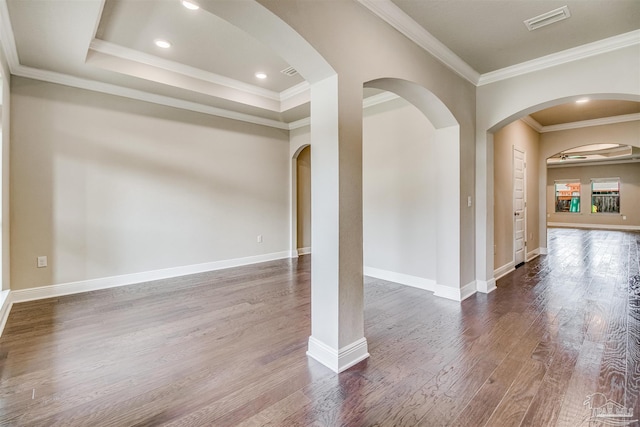 unfurnished room with dark wood-type flooring, ornamental molding, and a raised ceiling