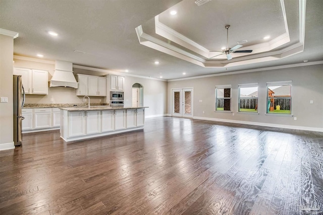 unfurnished living room featuring a raised ceiling, crown molding, and dark hardwood / wood-style flooring