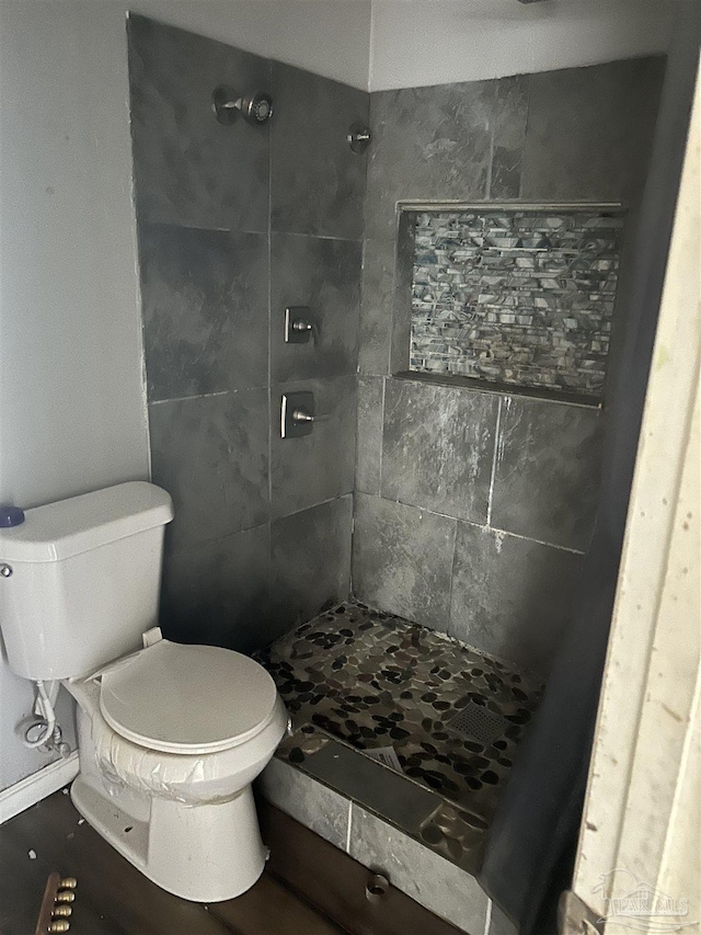 bathroom with a tile shower and toilet