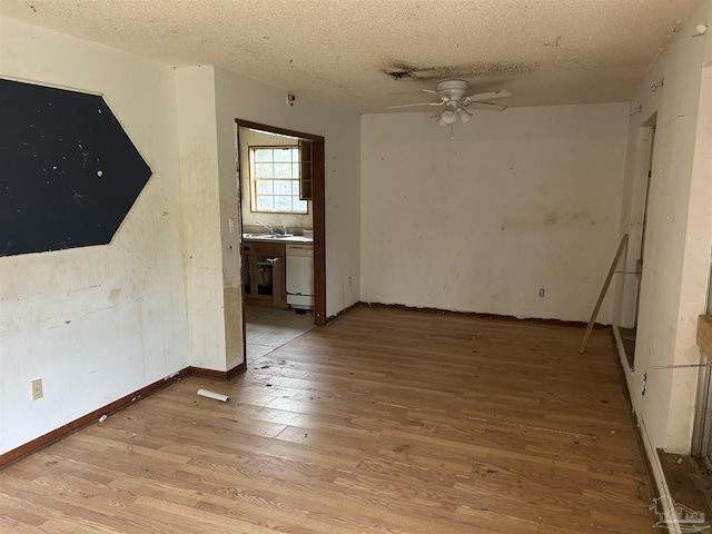 unfurnished room with ceiling fan, sink, a textured ceiling, and light hardwood / wood-style flooring