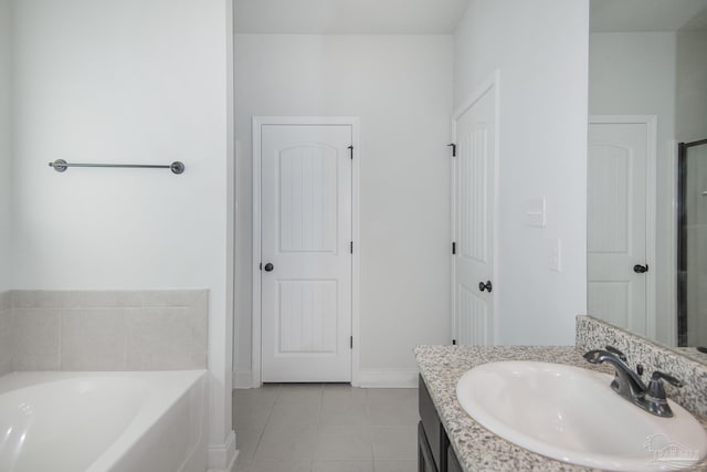 bathroom with tile patterned floors, vanity, and a tub to relax in