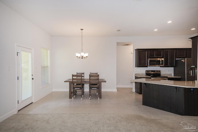 kitchen with a kitchen bar, hanging light fixtures, light tile patterned floors, and stainless steel appliances