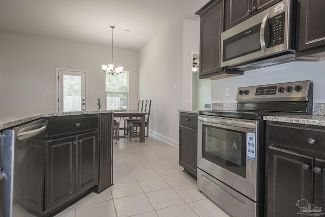 kitchen featuring light stone countertops, light tile patterned floors, stainless steel appliances, and an inviting chandelier