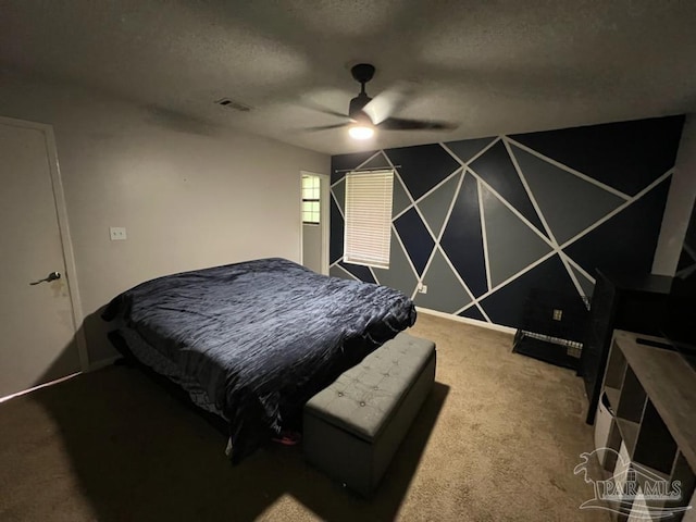 carpeted bedroom featuring ceiling fan and a textured ceiling