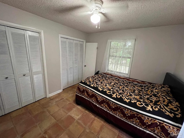 bedroom featuring ceiling fan, a textured ceiling, and multiple closets