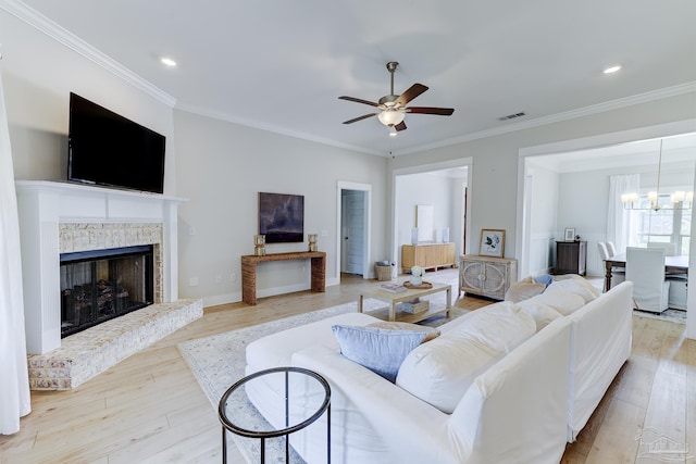 living room featuring crown molding, ceiling fan with notable chandelier, wood finished floors, and visible vents