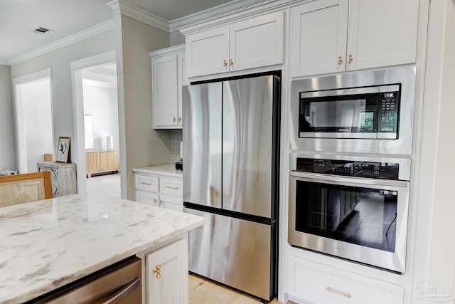 kitchen with crown molding, appliances with stainless steel finishes, light stone counters, and visible vents