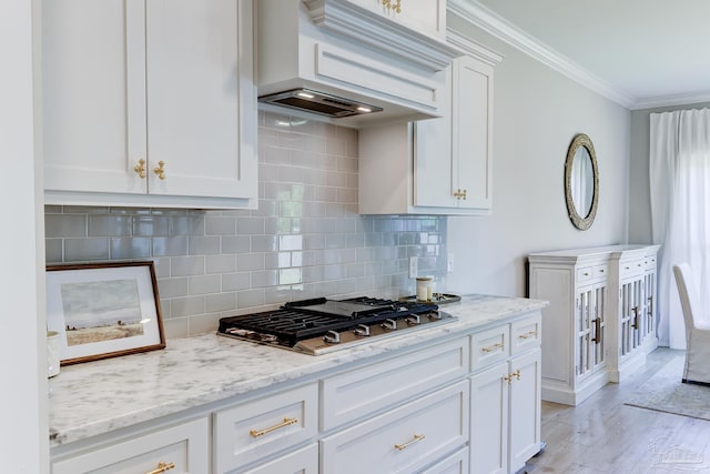 kitchen featuring crown molding, light stone countertops, stainless steel gas stovetop, tasteful backsplash, and custom exhaust hood