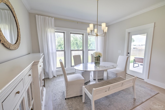 dining space featuring a healthy amount of sunlight, ornamental molding, light wood-type flooring, and a notable chandelier