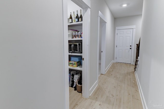 hall featuring baseboards and light wood finished floors