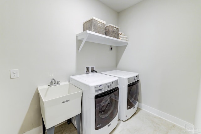 clothes washing area featuring laundry area, a sink, baseboards, and washing machine and clothes dryer