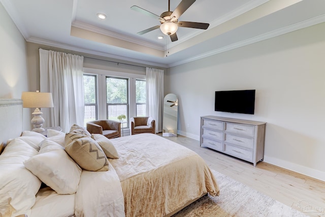 bedroom with crown molding, baseboards, a tray ceiling, and light wood-type flooring