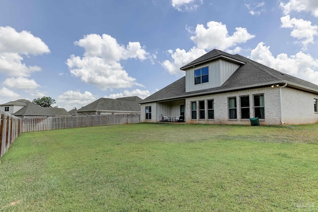 rear view of property with a lawn, brick siding, and a fenced backyard