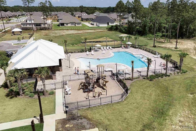community pool featuring fence, a lawn, and a residential view