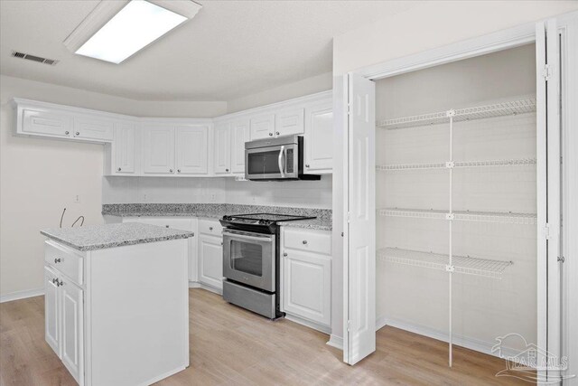kitchen featuring white cabinetry, appliances with stainless steel finishes, light wood finished floors, and visible vents