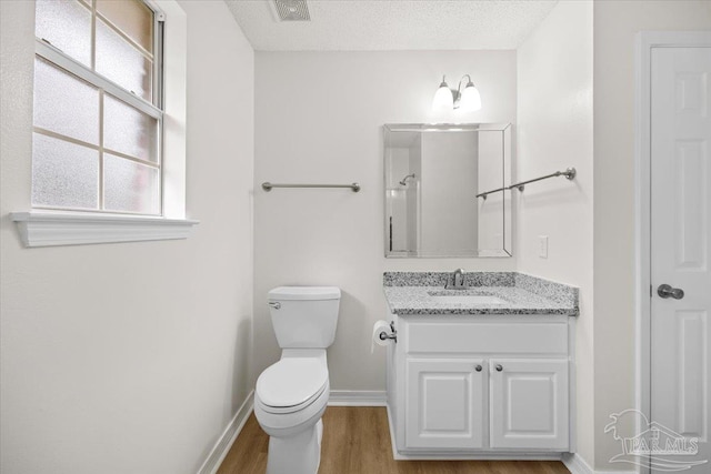 bathroom featuring wood finished floors, visible vents, toilet, vanity, and baseboards