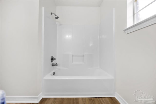 full bathroom featuring wood finished floors, baseboards, and bathtub / shower combination