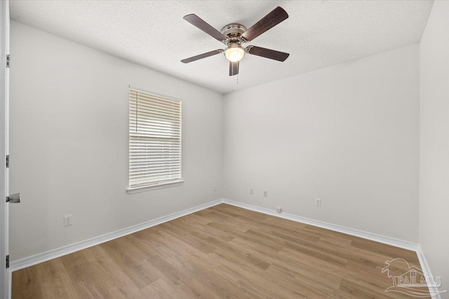empty room with a textured ceiling, light wood finished floors, baseboards, and ceiling fan