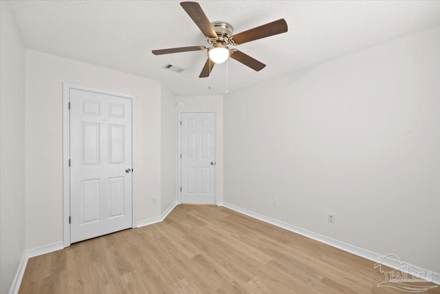 unfurnished bedroom with visible vents, a ceiling fan, baseboards, light wood-style flooring, and a textured ceiling