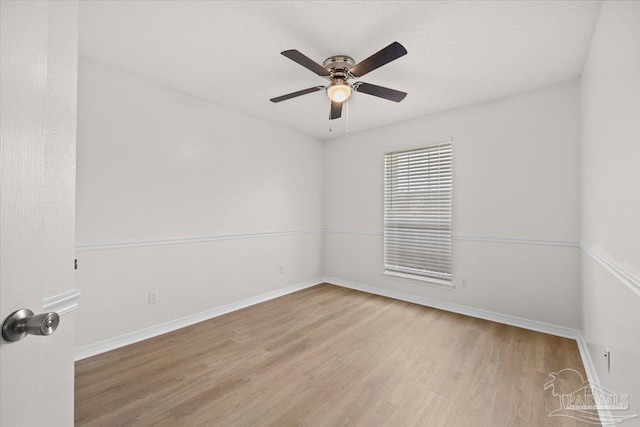 empty room featuring baseboards, wood finished floors, and ceiling fan