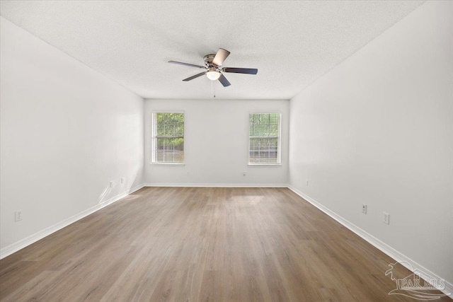 unfurnished room with baseboards, a ceiling fan, wood finished floors, and a textured ceiling