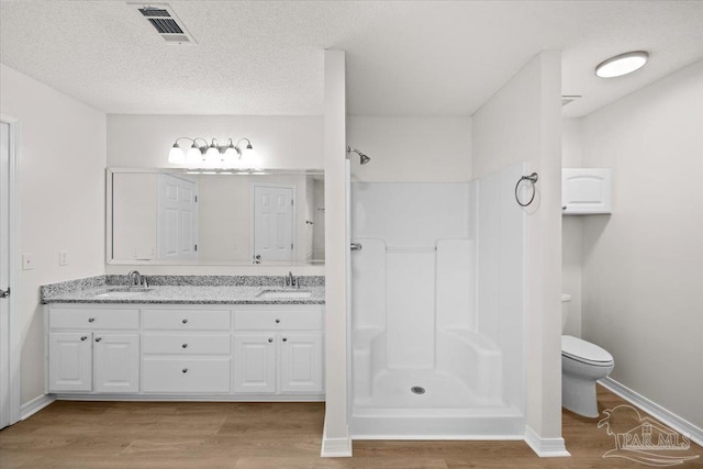 bathroom with walk in shower, wood finished floors, a sink, and visible vents