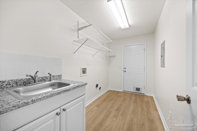 laundry room featuring hookup for a washing machine, a sink, electric panel, light wood-type flooring, and cabinet space