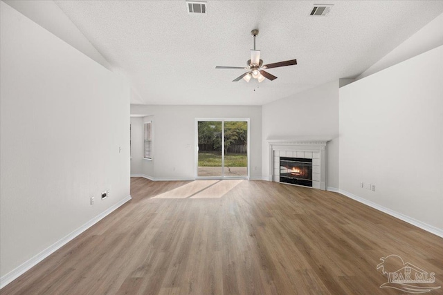 unfurnished living room featuring a textured ceiling, wood finished floors, visible vents, and a ceiling fan