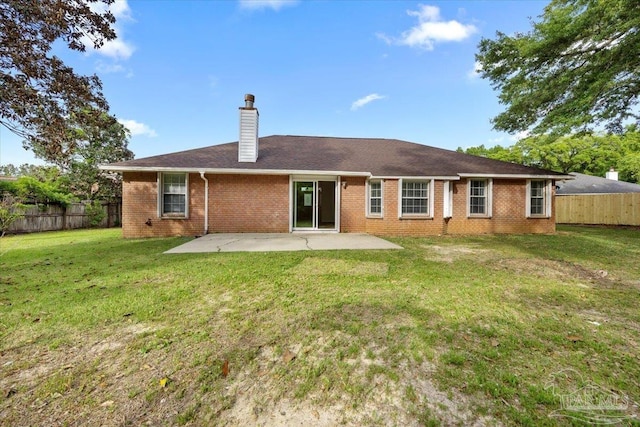 back of property with a fenced backyard, brick siding, and a patio