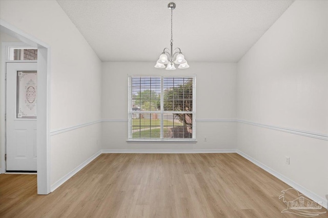 unfurnished dining area with baseboards, a chandelier, and light wood-style flooring