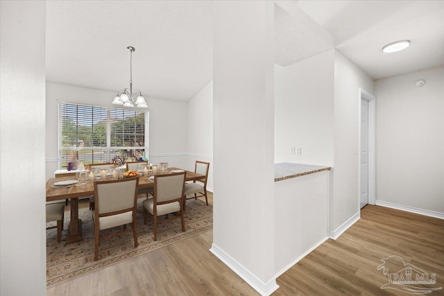 dining space featuring a chandelier, wood finished floors, and baseboards