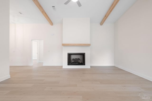 unfurnished living room featuring beamed ceiling, ceiling fan, a fireplace, and light wood-type flooring