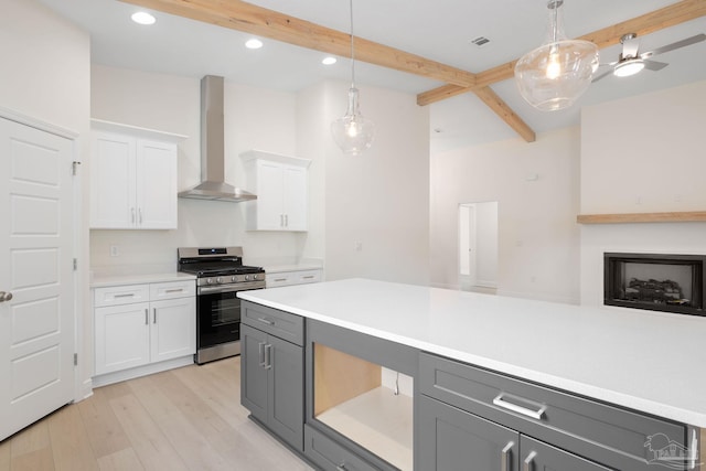 kitchen featuring gray cabinets, pendant lighting, white cabinetry, stainless steel gas range oven, and wall chimney range hood