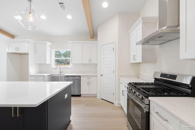 kitchen with wall chimney exhaust hood, sink, pendant lighting, stainless steel appliances, and white cabinets