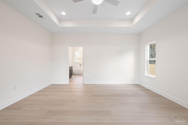 spare room with ceiling fan, light hardwood / wood-style floors, and a tray ceiling