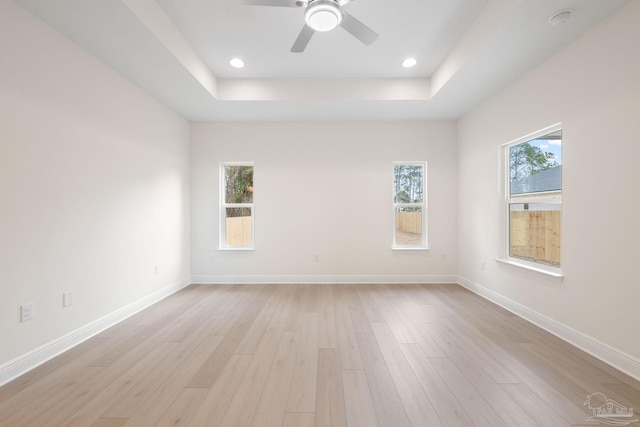 spare room featuring ceiling fan, light hardwood / wood-style floors, and a tray ceiling