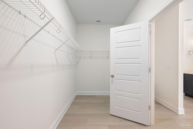 walk in closet with light hardwood / wood-style floors