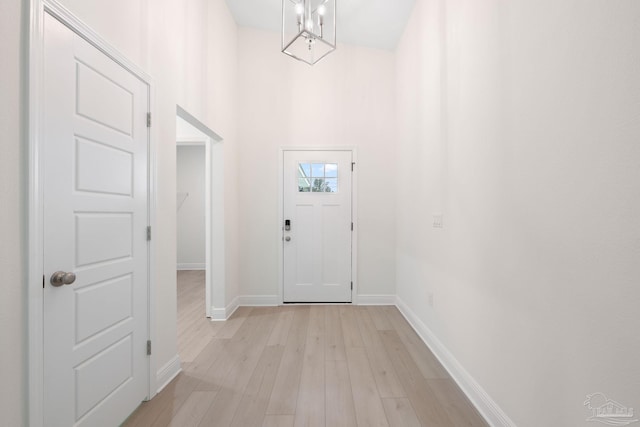 entryway featuring an inviting chandelier, light hardwood / wood-style flooring, and a high ceiling