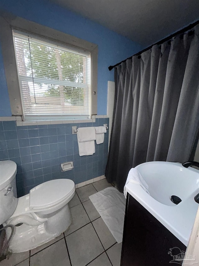 bathroom with tile patterned floors, vanity, toilet, and tile walls