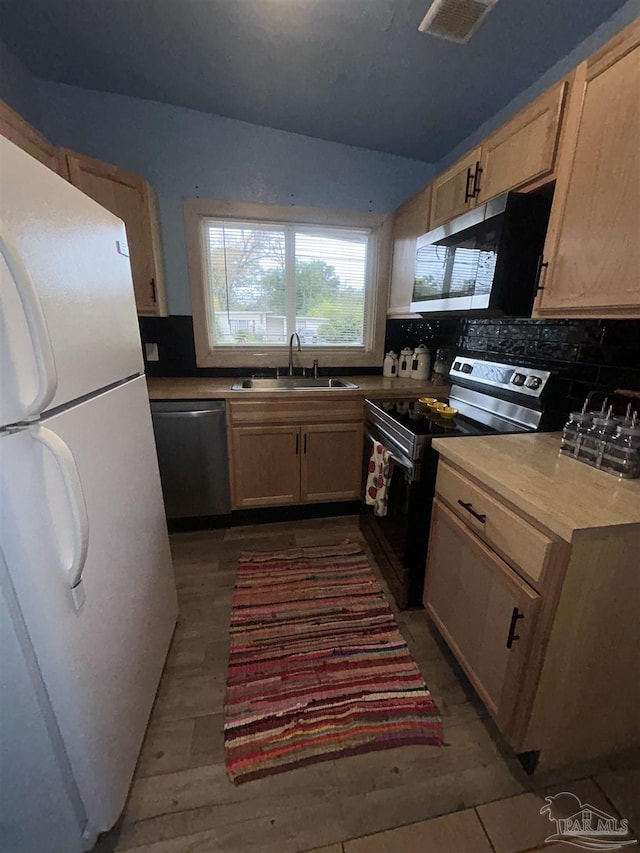 kitchen featuring light brown cabinets, sink, stainless steel appliances, and tasteful backsplash