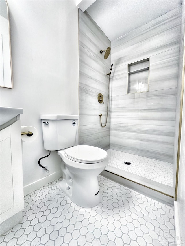 full bathroom with tile patterned floors, toilet, vanity, and a tile shower