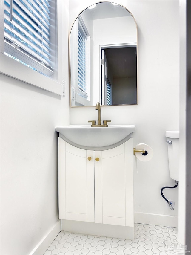 bathroom with baseboards, toilet, and vanity
