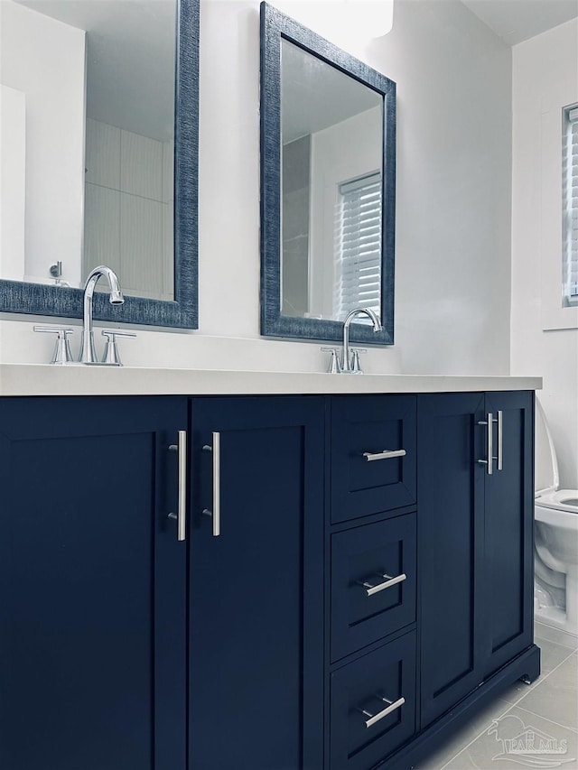 bathroom featuring tile patterned floors, a sink, toilet, and double vanity