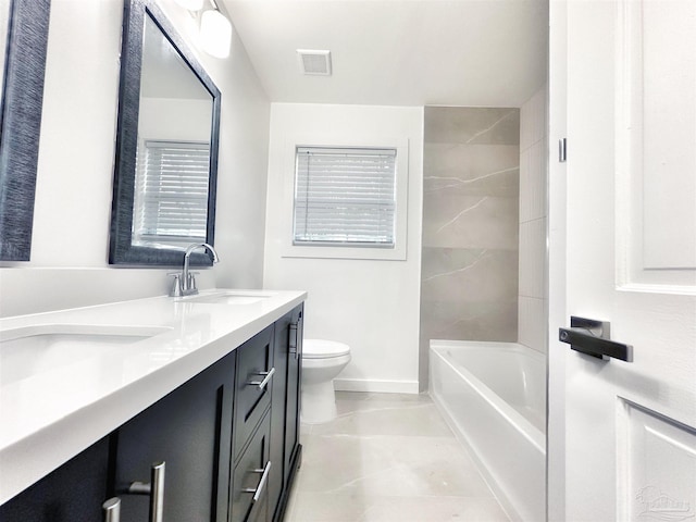 bathroom featuring visible vents, baseboards, toilet, double vanity, and a sink