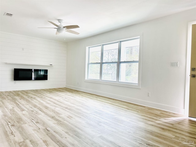 unfurnished living room with visible vents, a ceiling fan, wood finished floors, a large fireplace, and baseboards