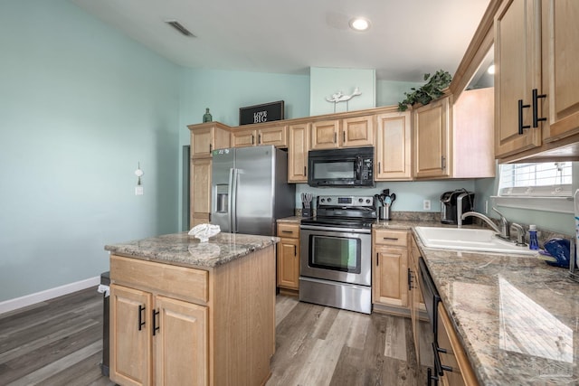 kitchen featuring lofted ceiling, a sink, black appliances, and light brown cabinetry