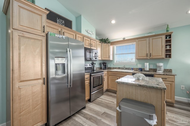 kitchen featuring black appliances, light brown cabinets, light wood-style floors, and a sink