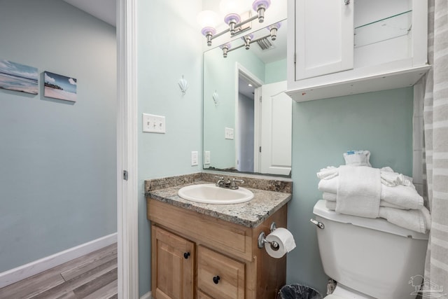 bathroom featuring toilet, baseboards, wood finished floors, and vanity