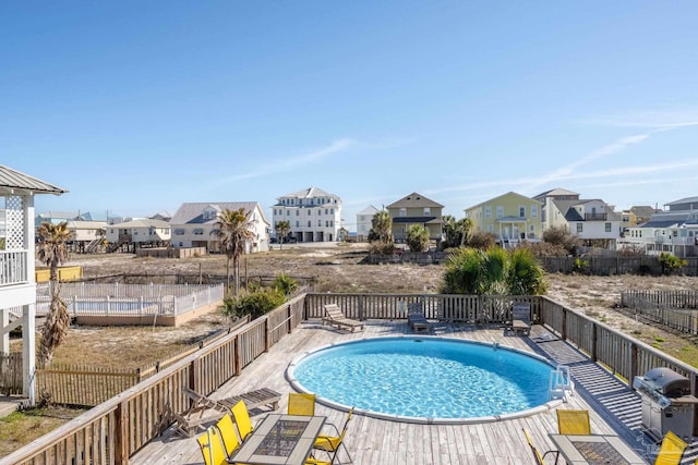 view of swimming pool featuring a grill, fence, a residential view, and a fenced in pool