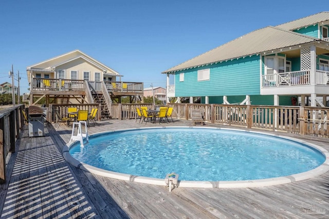 outdoor pool featuring outdoor dining space, a grill, and a wooden deck